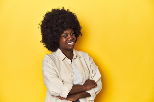 Foto afroamerikanische frau mit afro-studio gelbem hintergrund verdächtig unsicher untersucht sie