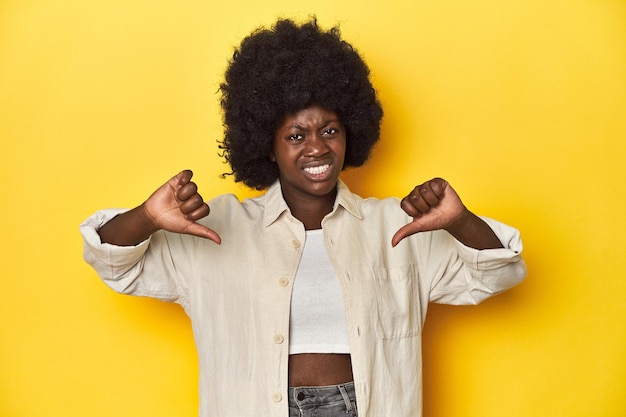 Afroamerikanische Frau mit afro-studio-gelbem Hintergrund zeigt Daumen nach unten und drückt Abneigung aus