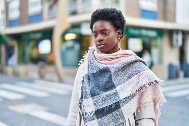 Afroamerikanische Frau mit entspanntem Gesichtsausdruck steht auf der Straße