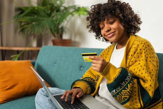 Afroamerikanische Frau mit Laptop-Shopping online bezahlt mit Gold-Kreditkarte Mädchen sitzt an