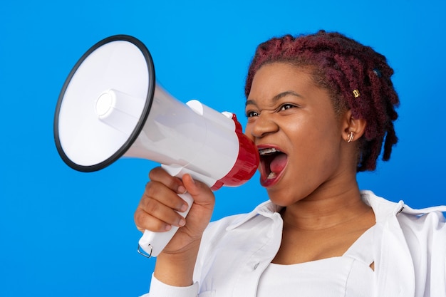 Afroamerikanische Frau mit Megaphon vor blauem Hintergrund