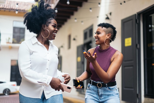 Afroamerikanische Frauen reden und lachen, während sie in der Stadt spazieren gehen.