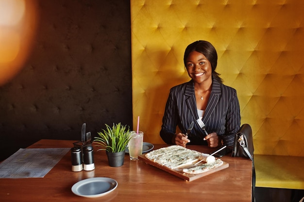 Afroamerikanische Geschäftsfrau, die Käsepizza im Café isst Schwarzes Mädchen, das sich ausruht