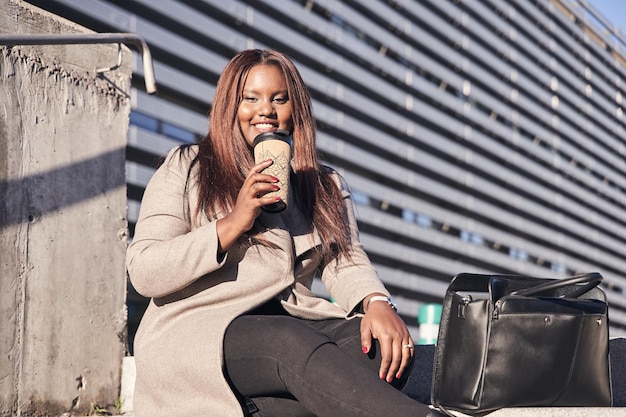 Afroamerikanische Geschäftsfrau wartet am Flughafen mit einem heißen Getränk