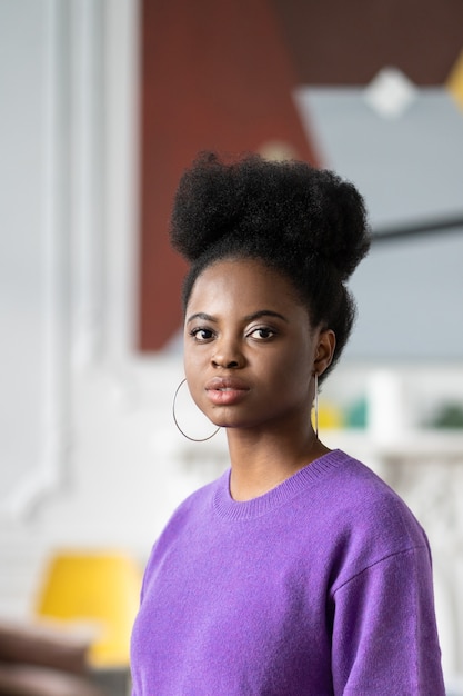 Afroamerikanische junge Frau mit lockiger Afro-Frisur trägt lila Pullover