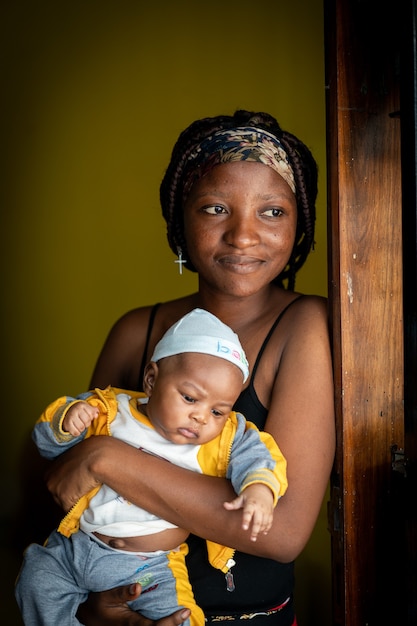 Afroamerikanische junge Mutter, die ihr Baby drinnen hält