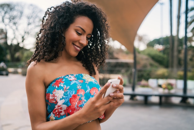 Afroamerikanische lateinische Frau, die Handy verwendet.