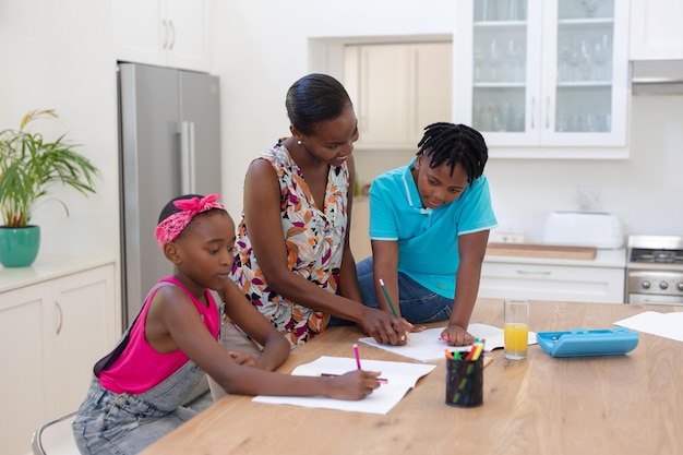 Afroamerikanische Mutter mit Tochter und Sohn bei Schularbeiten in der Küche