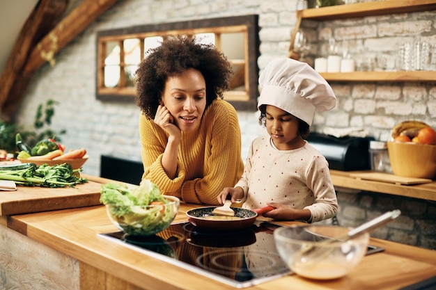 Afroamerikanische Mutter und Tochter bereiten in der Küche eine Mahlzeit zu