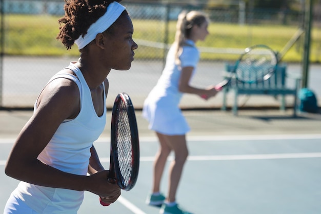 Afroamerikanische Spielerin spielt Tennis mit einem kaukasischen Doppelpartner auf dem Platz