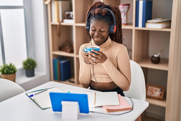 Afroamerikanische Studentin hört Musik und trinkt zu Hause Kaffee