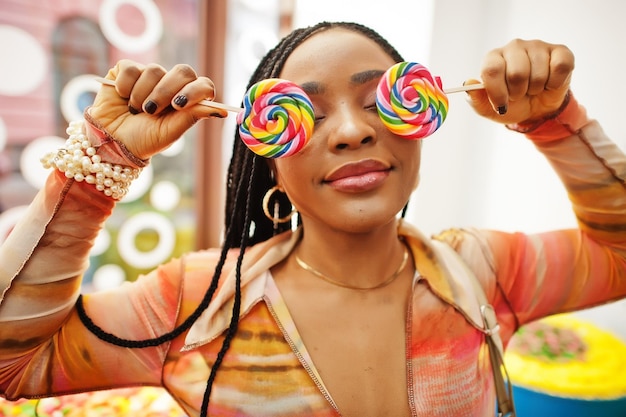 Afroamerikanische tausendjährige Dame im Süßwarenladen mit Lolipops bedecken ihre Augen