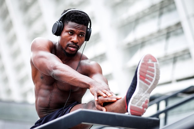 Afroamerikanischer athletischer Typ, der im Sommer im Freien trainiert sportlicher Mann ohne Hemd beim Aufwärmen