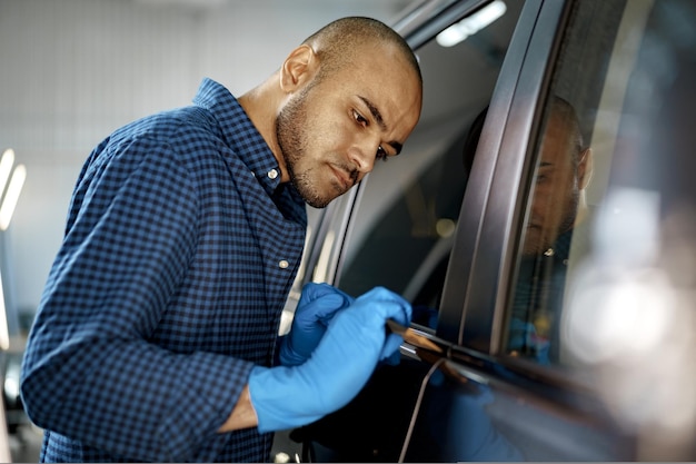 Afroamerikanischer Autoservice-Mitarbeiter, der eine Nanobeschichtung auf ein Auto aufträgt