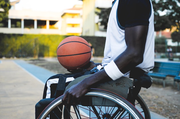 Foto afroamerikanischer basketballspieler im rollstuhl, der darauf wartet, auf dem open-air-grundkonzept der zugänglichkeit zum sport für behinderte sportler soziale eingliederung zu spielen