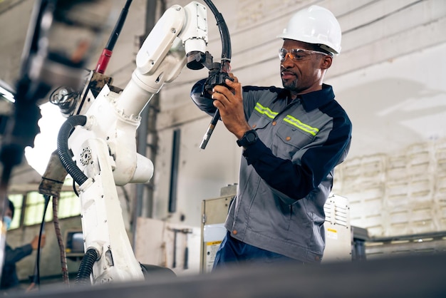 Afroamerikanischer Fabrikarbeiter, der mit einem geschickten Roboterarm arbeitet