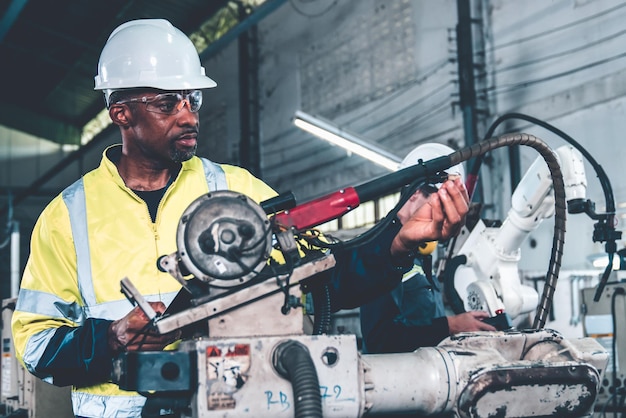 Afroamerikanischer Fabrikarbeiter, der mit einem geschickten Roboterarm arbeitet