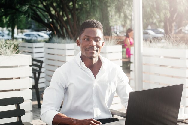 Afroamerikanischer Geschäftsmann, der an einem Laptop in einem Café arbeitet