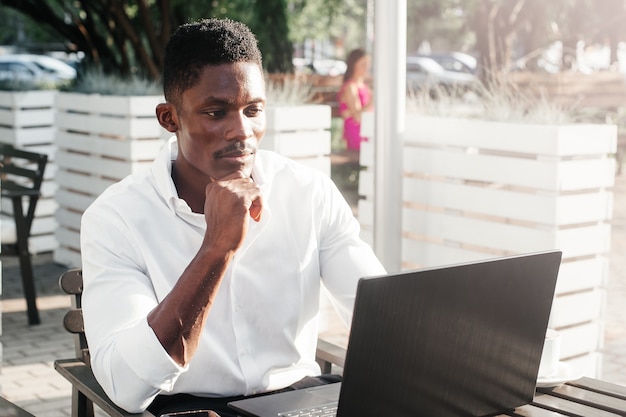 Afroamerikanischer Geschäftsmann, der an einem Laptop in einem Café arbeitet