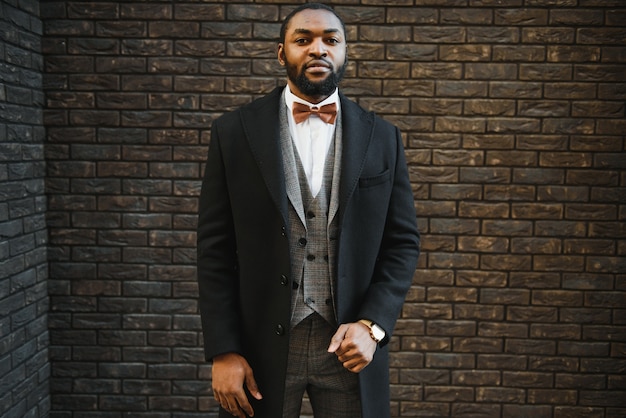 Afroamerikanischer Geschäftsmann, der einen Anzug trägt, der in einer Geschäftsumgebung im Freien steht