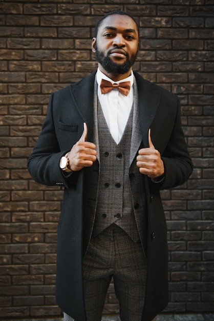 Afroamerikanischer Geschäftsmann, der einen Anzug trägt, der in einer Geschäftsumgebung im Freien steht