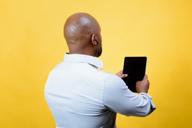 afroamerikanischer Geschäftsmann, der Technologie auf gelbem Hintergrund handhabt