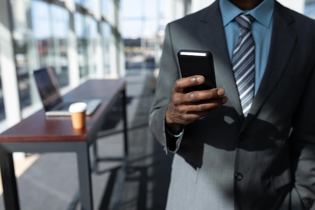 Foto afroamerikanischer geschäftsmann mit mobiltelefon im büro