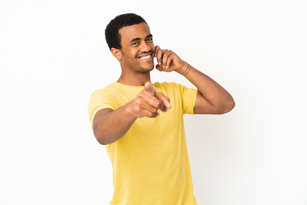 Afroamerikanischer gutaussehender Mann mit Handy über isoliertem weißem Hintergrund, der nach vorne mit glücklichem Ausdruck zeigt