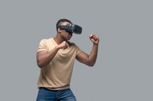 Afroamerikanischer junger Mann in VR-Brille beim Spielen und Boxen