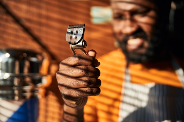 Afroamerikanischer junger Mann mit tragbarem Haarschneider