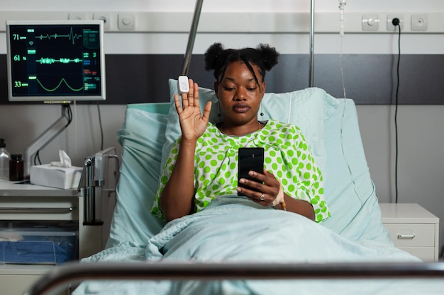 Afroamerikanischer kranker Patient, der Smarphone-Grüße entfernter Freunde hält und medizinisches Fachwissen während der Online-Videokonferenz-Konferenz erklärt. Telekommunikationskonzept. Medizinservice