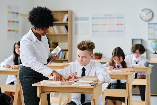 Afroamerikanischer Lehrer spricht während des Unterrichts in der Schule mit einem Schüler