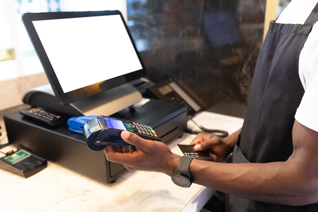 Foto afroamerikanischer männlicher barista nutzt die kreditkarte des kunden zur zahlung in einem café. unabhängiger kleinunternehmer.