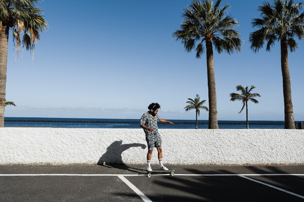 Afroamerikanischer Mann, der Longboard mit Strand im Hintergrund reitet - Fokus auf Gesicht