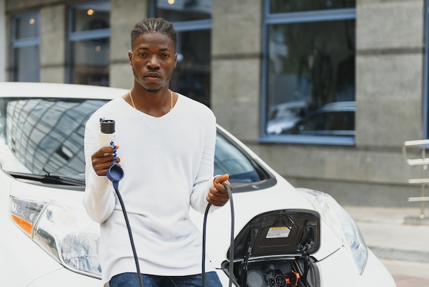 Afroamerikanischer Mann, der sein Elektroauto auflädt.