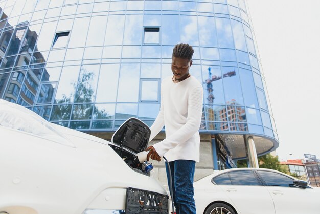 Afroamerikanischer Mann, der sein Elektroauto auflädt.