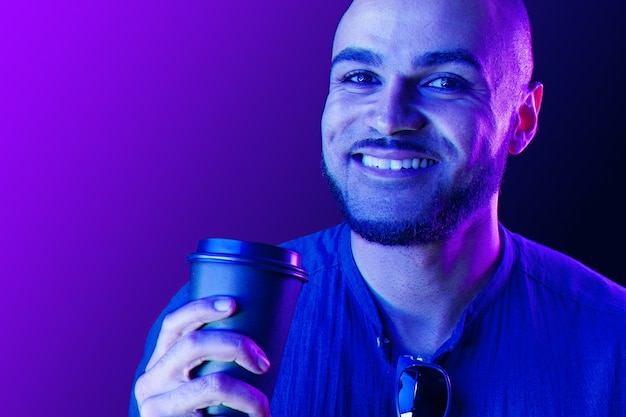 Afroamerikanischer Mann, der Tasse Kaffee im Neonlicht nah oben hält