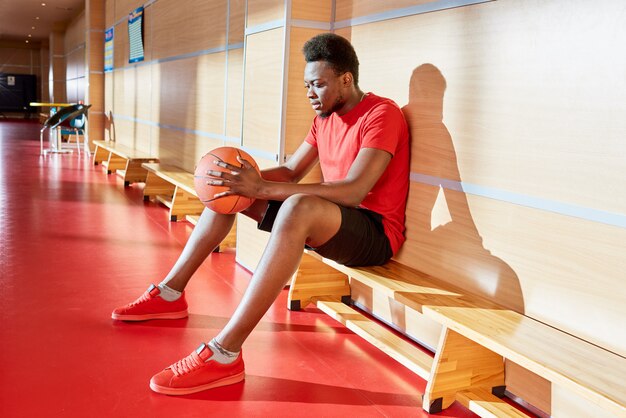 Afroamerikanischer Mann mit Basketballball auf Bank