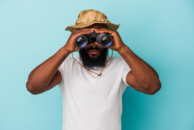 Afroamerikanischer Mann mit Fernglas auf blauem Hintergrund isoliert