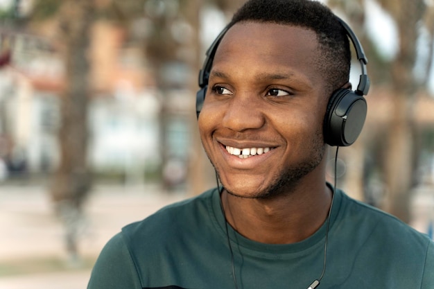 Afroamerikanischer Mann mit Kopfhörern, der sich vor dem Rennen auf der Straße entspannt