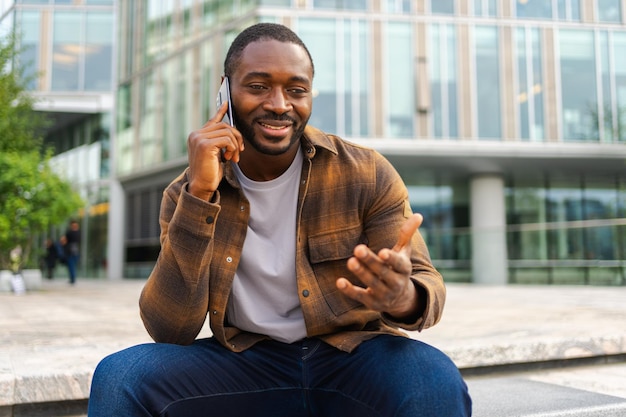 Afroamerikanischer Mann spricht mit Smartphone auf der Straße in der Stadt, Mann im Freien mit Handy-Chat