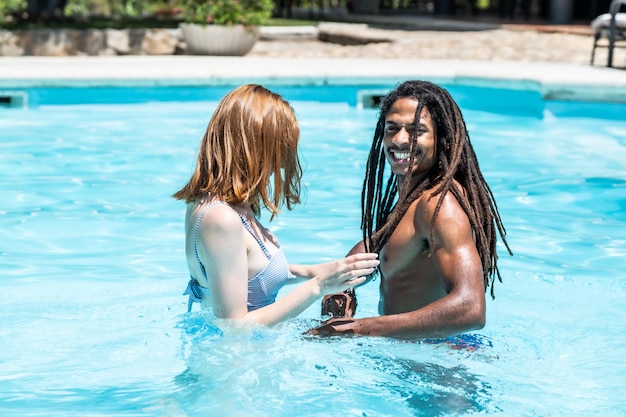 Afroamerikanischer Mann und weiße Frau, die in einem Pool spielen.