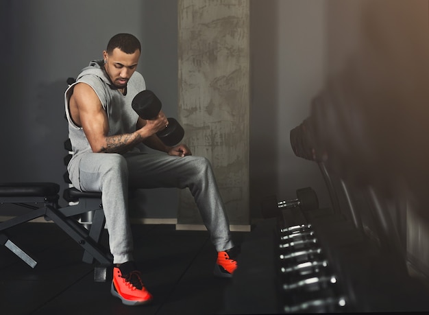 Afroamerikanischer muskulöser Bodybuilder, der schwere Kreuzheben im modernen Fitnesscenter macht. Starker Mann, der mit Hanteln im Fitnessstudio trainiert, Platz kopieren