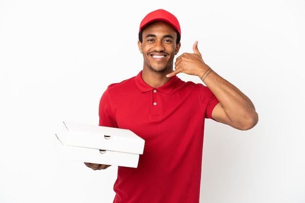 Afroamerikanischer Pizzabote, der Pizzakartons über isolierte weiße Wand aufhebt und Telefongeste macht. Ruf mich zurück Zeichen