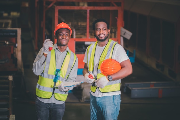 Afroamerikanischer schwarzer Afro-Arbeiter in Fabrik Zwei Ingenieure der Schwerindustrie stehen in einer Stahl-Metall-Fertigungsfabrik und Diskussion Schwarzer afroamerikanischer Industriespezialist spricht mit Techniker