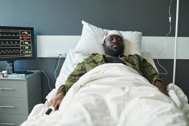 Afroamerikanischer Soldat mit Kopf umwickelt von Verband im Bett liegend