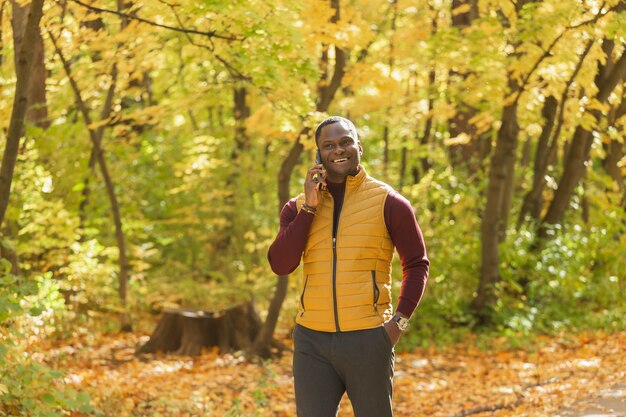 Afroamerikanischer Student, der in der Herbstsaison im Park spazieren geht