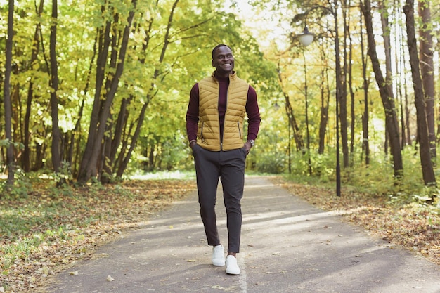 Afroamerikanischer Student, der in der Herbstsaison im Park spazieren geht.