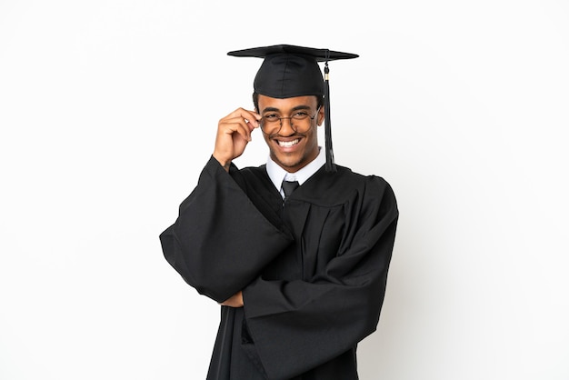 Afroamerikanischer Universitätsabsolvent über isoliertem weißem Hintergrund mit Brille und glücklich