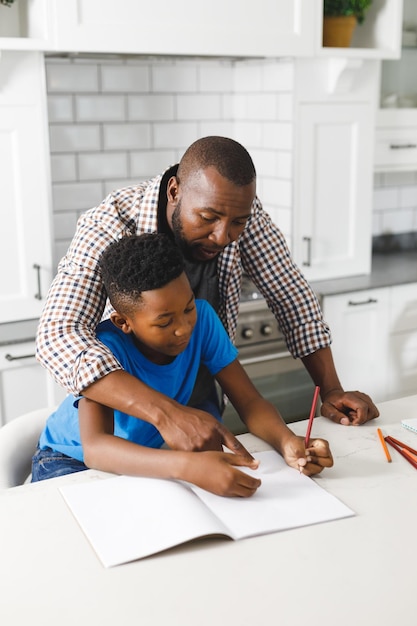 Afroamerikanischer Vater und sein Sohn in der Küche, gemeinsam Hausaufgaben machen